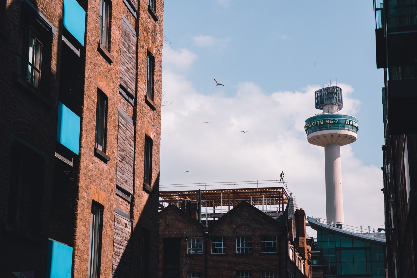Silhouetted figure on a rooftop with the Liverpool Radio City tower in the background