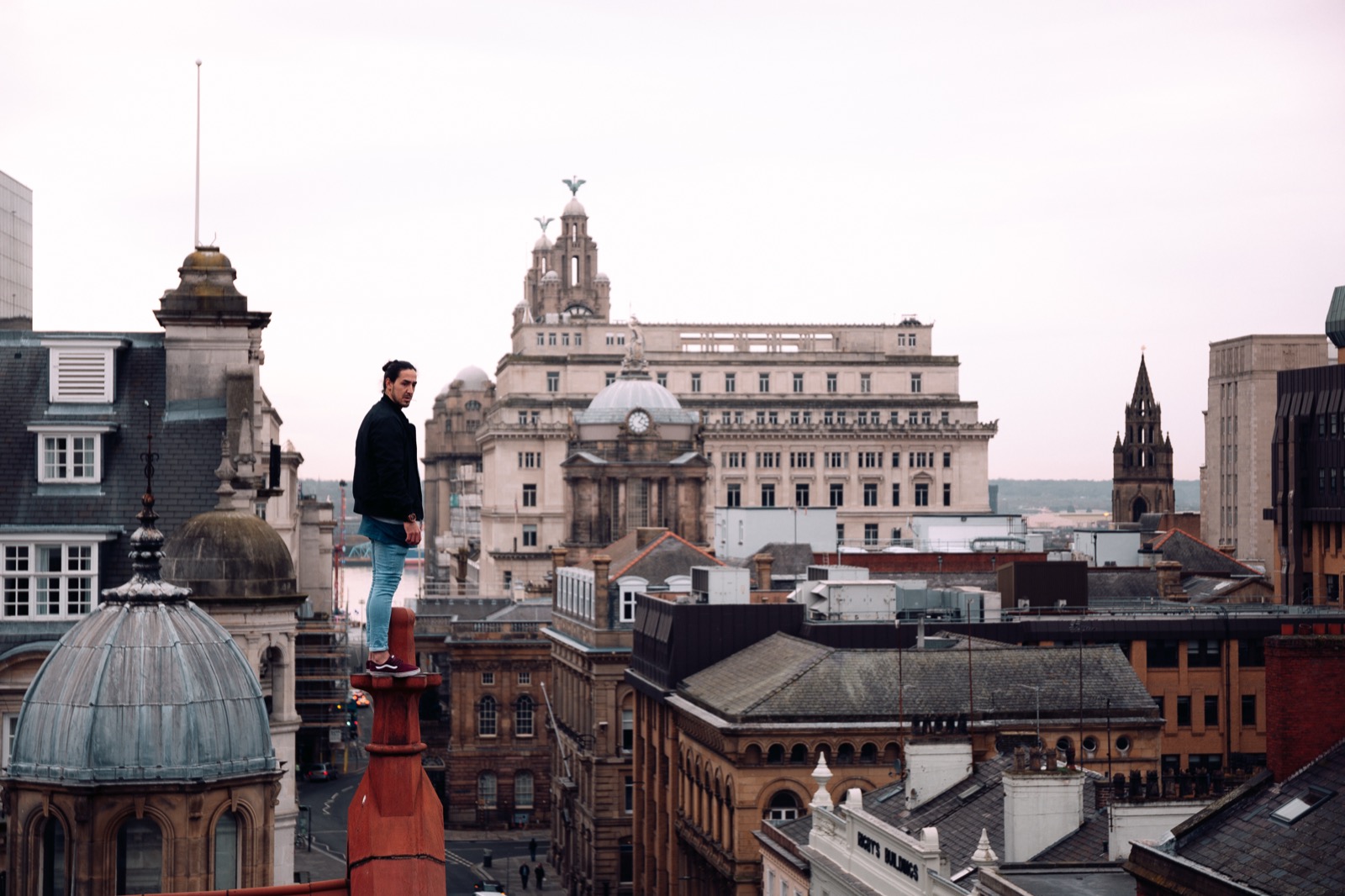 Athlete standing on a rooftop chimney overlooking the Liverpool skyline